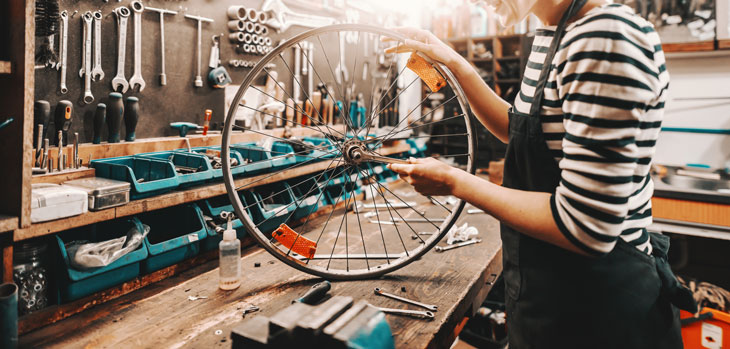 Woman holding a bicycle wheel in a workshop.