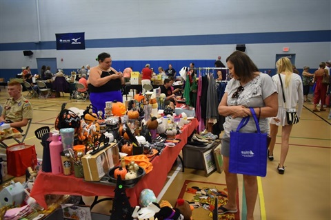 Shopper looking at a table filled with fall decorations and other items at the Wickham Park Community Center Rummage Sale