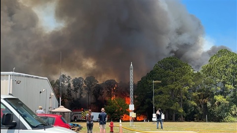 Bystanders watch as a fire in a wooded area creates a large column of smoke and Melbourne Fire Engine 71 responds.