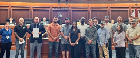 Public Works and Utilities employees standing with Mayor Alfrey in the Council Chamber after the reading of the Florida Water Professionals Month proclamation. 