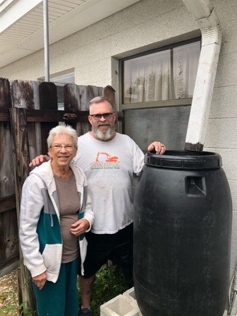 Earleen and Jason with installed rain barrel next to their house 