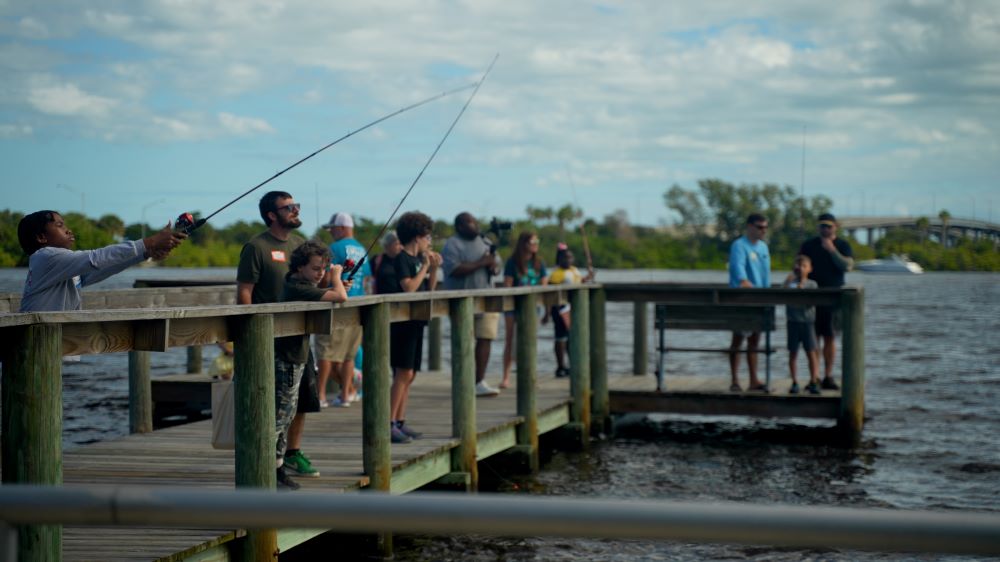 Kids fishing off Front Street Park dock with with adults helping some of them
