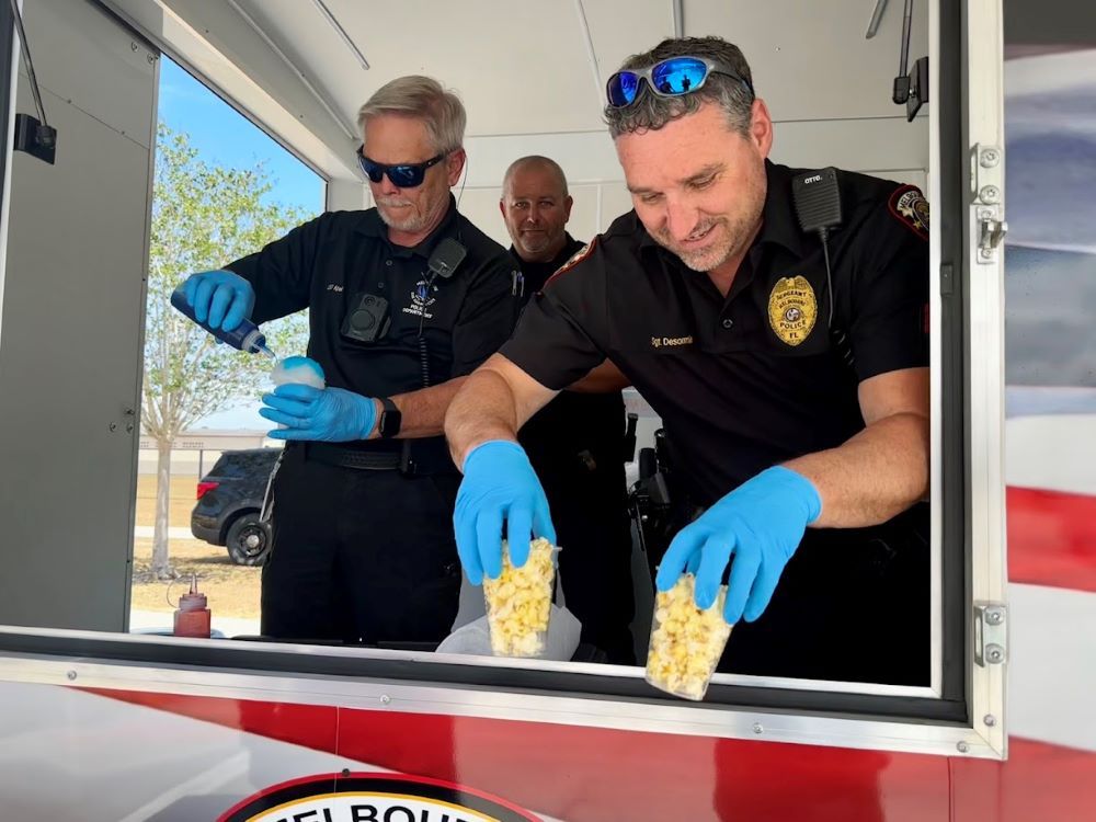 Police officers serving popcorn and snow cones from Community Services vehicle